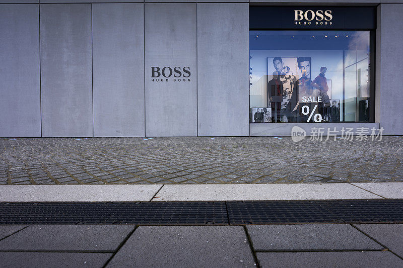 Hugo Boss Outlet商店。黑色门面下有人体模型的商店橱窗。前景是鹅卵石。前视图。